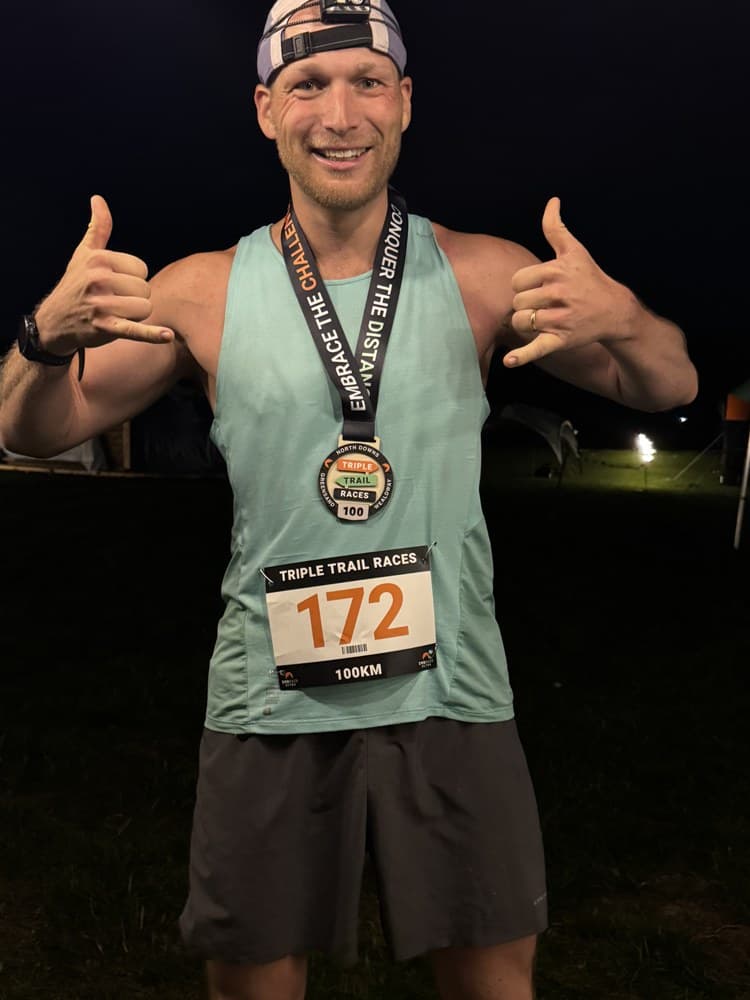 Sven nachts im Ziel des Triple Trail Ultra mit Finisher-Medaille