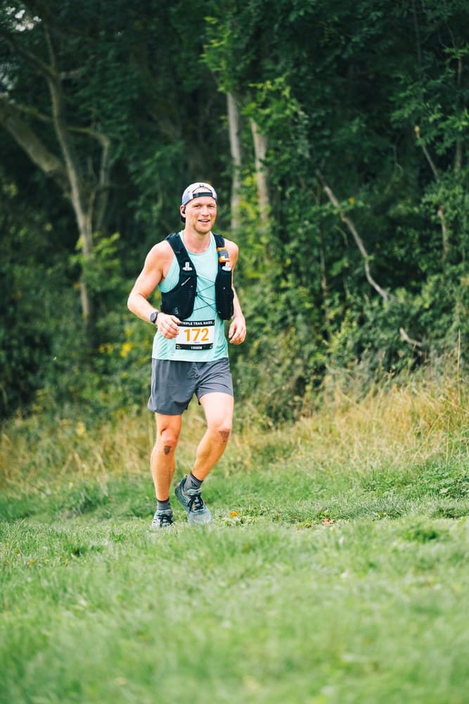 Sven läuft mit Startnummer durch einen Wald beim Trail-Ultra